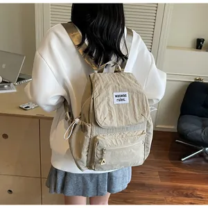 Detail of beige wrinkled nylon backpack with brand label and drawstring side pockets