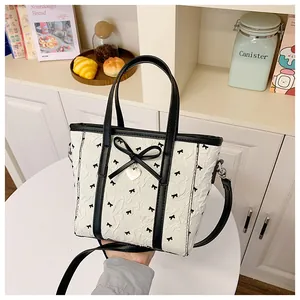 Détail du sac cabas blanc à imprimé nœuds noirs, texture plissée et cœur métal