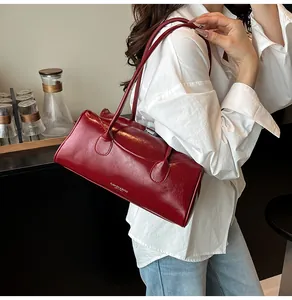 Detail view of glossy deep red leather shoulder bag with sleek slim straps and white text