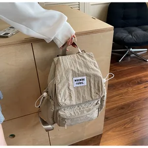 Detail of beige nylon backpack featuring drawstring closure and textured fabric