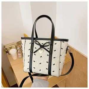 Détail du sac cabas crème avec pendentif cœur et imprimé nœud sur texture plissée