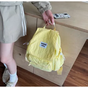 Close-up of lightweight pale yellow nylon backpack with drawstring closure and label detail