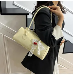 Chic cream leather shoulder bag with cherry and pearl charm on a minimalist staircase