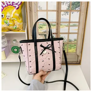Détail du mini sac cabas rose clair avec motifs de nœuds noirs et breloque en cœur