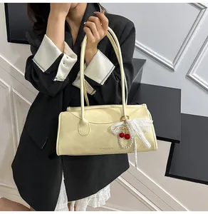Detail of cream leather shoulder bag featuring a cherry charm and white lace bow