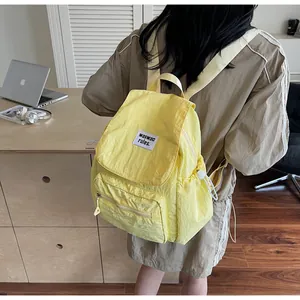 Close-up of bright yellow nylon backpack featuring functional pockets and text patch
