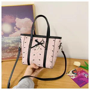 Détail du sac cabas plissé rose avec nœud noir et pendentif cœur sur bois