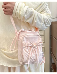 Détail d'un sac bandoulière rose avec nœud décoratif et fermeture à cordon pratique