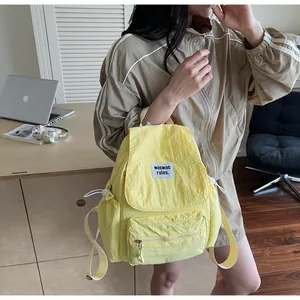 Detail of light yellow nylon backpack with white drawstring side pockets and logo label