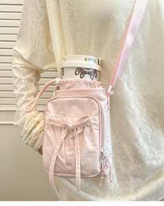 Vue détaillée du sac à bandoulière rose avec nœud, cordon de serrage et gourde dessin animé