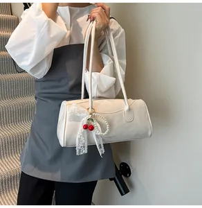 Close-up of a cream white PU leather handbag with cherry charm and pearl lace bow detail