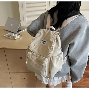 Rear view of model wearing a minimalist off-white nylon backpack in a cozy indoor setting