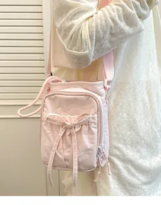 Gros plan du sac à bandoulière rose léger avec nœud papillon et plusieurs fermetures