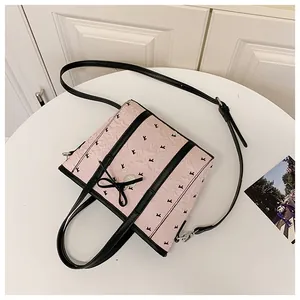 Détail du sac rose montrant les finitions en cuir noir, le nœud et le pendentif cœur