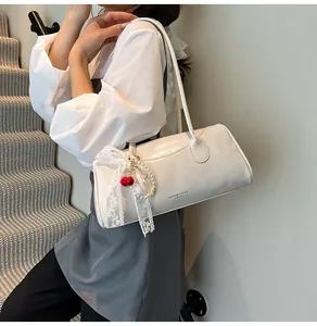Detail of a chic cream leather handbag with lace ribbon, cherry charm, and pearl chain