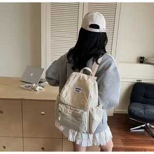 Detail of off-white nylon backpack showing the front flap, logo patch and zipper pockets