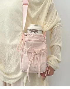 Détail macro du sac bandoulière en nylon rose avec nœud et fermeture à cordon