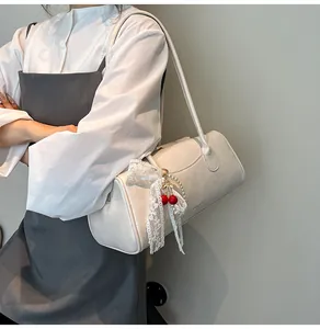 Detail of cream Boston shoulder bag featuring lace bow and cherry pearl charm