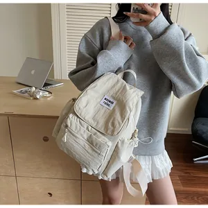 Detail of minimalist beige backpack with embroidered patch and front zipper pocket