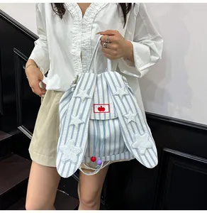 Detail of blue striped canvas backpack with rabbit ears and plush star decorations