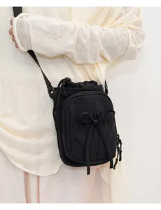 Vue détaillée du sac bandoulière en nylon noir avec nœud décoratif et bandoulière réglable