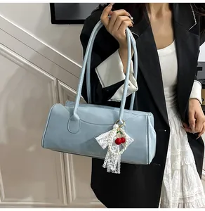 Close-up of light blue rectangle shoulder bag with cherry lace charm on smooth leather