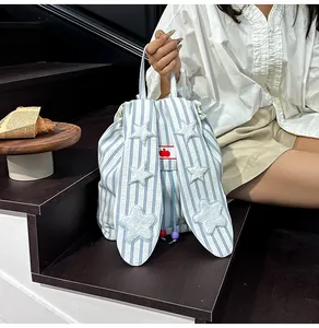 Detail of striped drawstring backpack with plush stars on bunny ear straps and red apple logo
