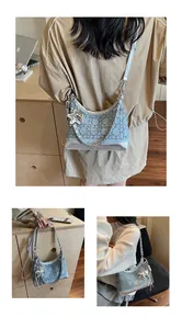 Detail of blue denim hobo bag featuring silver trim, chain strap, and butterfly charm