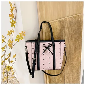 Détail du sac cabas rose avec nœuds noirs, texture matelassée et breloque en cœur