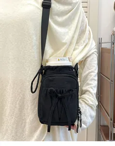 Détail du sac à bandoulière noir pour gourde avec nœud décoratif et sangle réglable