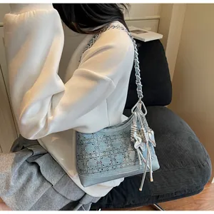 Detail of blue denim hobo bag featuring silver rhinestone grid and butterfly tassel charm