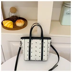Détail du sac fourre-tout blanc en tissu plissé avec motifs nœuds noirs et doubles anses