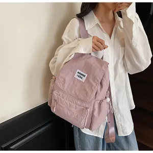 Detailed view of dusty rose textured nylon backpack with white logo tag on the front