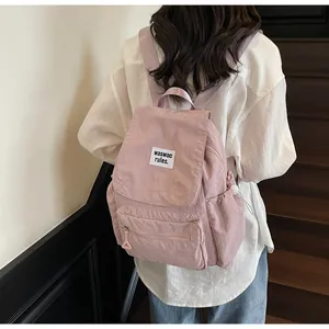 Detail of a pink casual nylon backpack featuring a brand patch and drawstring side pocket