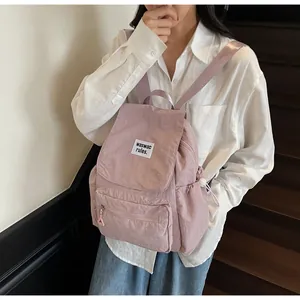 Detail of light purple nylon backpack showing front zip pocket and fabric texture