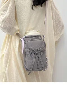 Gros plan d'un sac bandoulière gris à nœud contenant une gourde et sa sangle