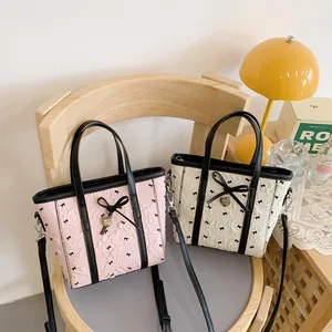 Sacs cabas gaufrés rose et beige avec nœuds noirs et breloques cœur sur une chaise en bois