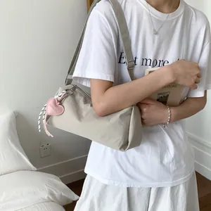Minimalist beige nylon crossbody bag for women with a cute pink heart pendant charm
