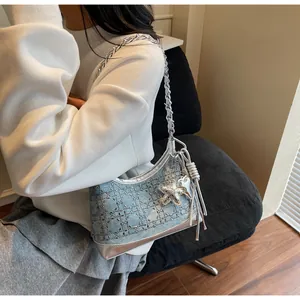 Detail of light blue denim handbag featuring silver studs, sequins, and star charm accessory