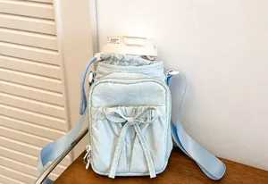 Detalle de bolso de nailon azul claro con lazo decorativo y correa de hombro ajustable