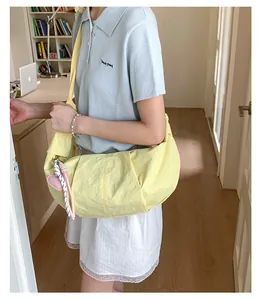 Detail der hellgelben Halbmond-Tasche mit Herzanhänger und geflochtener Seil-Verzierung