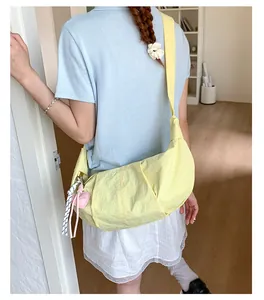 Detail der gelben Nylon-Tasche mit Faltendesign und rosa Herzanhänger am Gurt