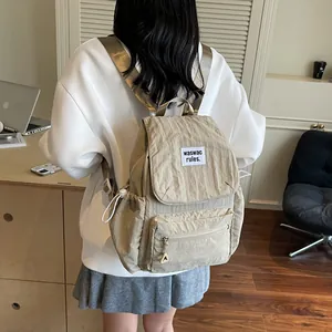 Beige nylon backpack for women with drawstring pockets and adjustable straps in home setting