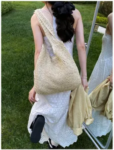 Outdoor shot of a beige woven straw tote bag with wide straps on a model with mirror reflection