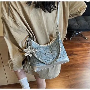 Detail of denim crossbody bag with beaded checkerboard pattern and silver metallic straps