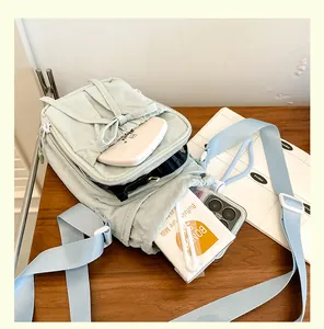 Vue intérieure du sac bandoulière en nylon vert clair montrant le rangement du mobile