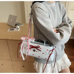 Detail of light blue bow handbag featuring lace edges and red checkered ribbon accents