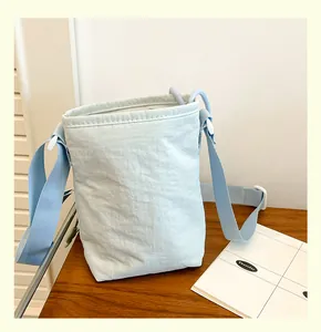 Détail du sac bandoulière en nylon bleu clair avec texture plissée et sangle réglable