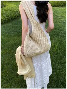 Outdoor view of a beige hand-woven crochet tote bag on a model in a summer garden