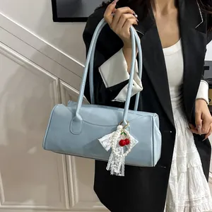 Light blue faux leather shoulder bag with decorative cherry pearl bow charm on casual model